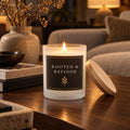 Rooted & Refined black label frosted glass candle lit in a dark, moody living room
