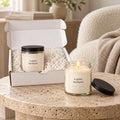 A quiet moment candle gift set: open gift box and a lit candle on a stone side table in a calm living room
