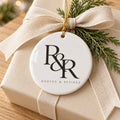 White ceramic ornament with a black R&R monogram on a cream gift wrapped with a linen bow and cedar