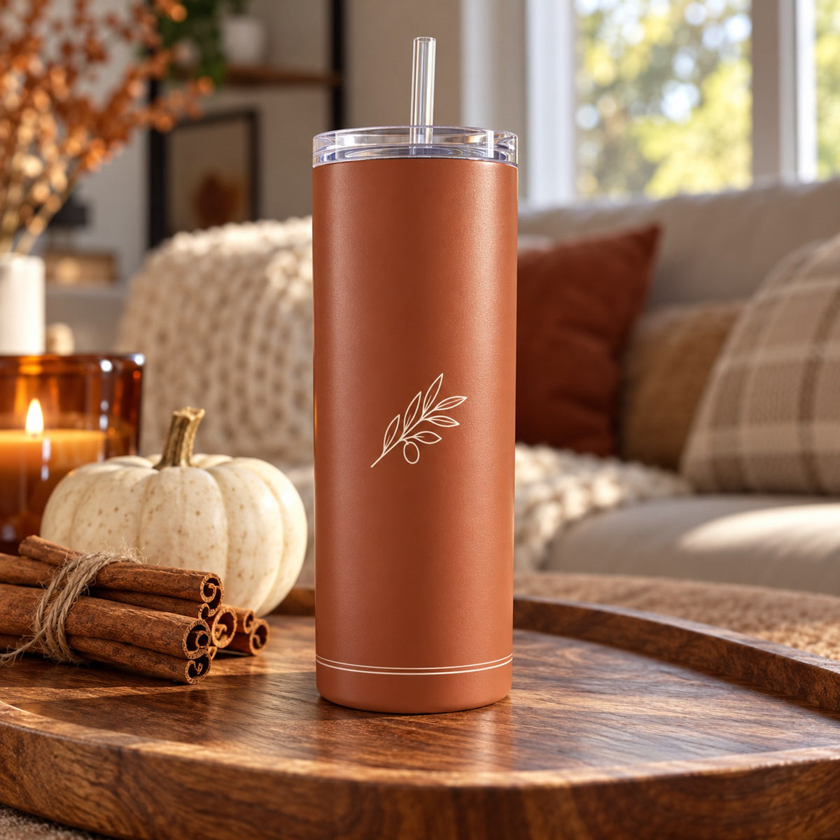 Cinnamon tumbler with a cream olive branch on a wood tray with cinnamon sticks, a white pumpkin and a candle