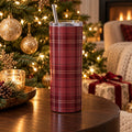 Cranberry tartan 20 oz tumbler on a round wood table beside a lit Christmas tree, candle and wrapped gift