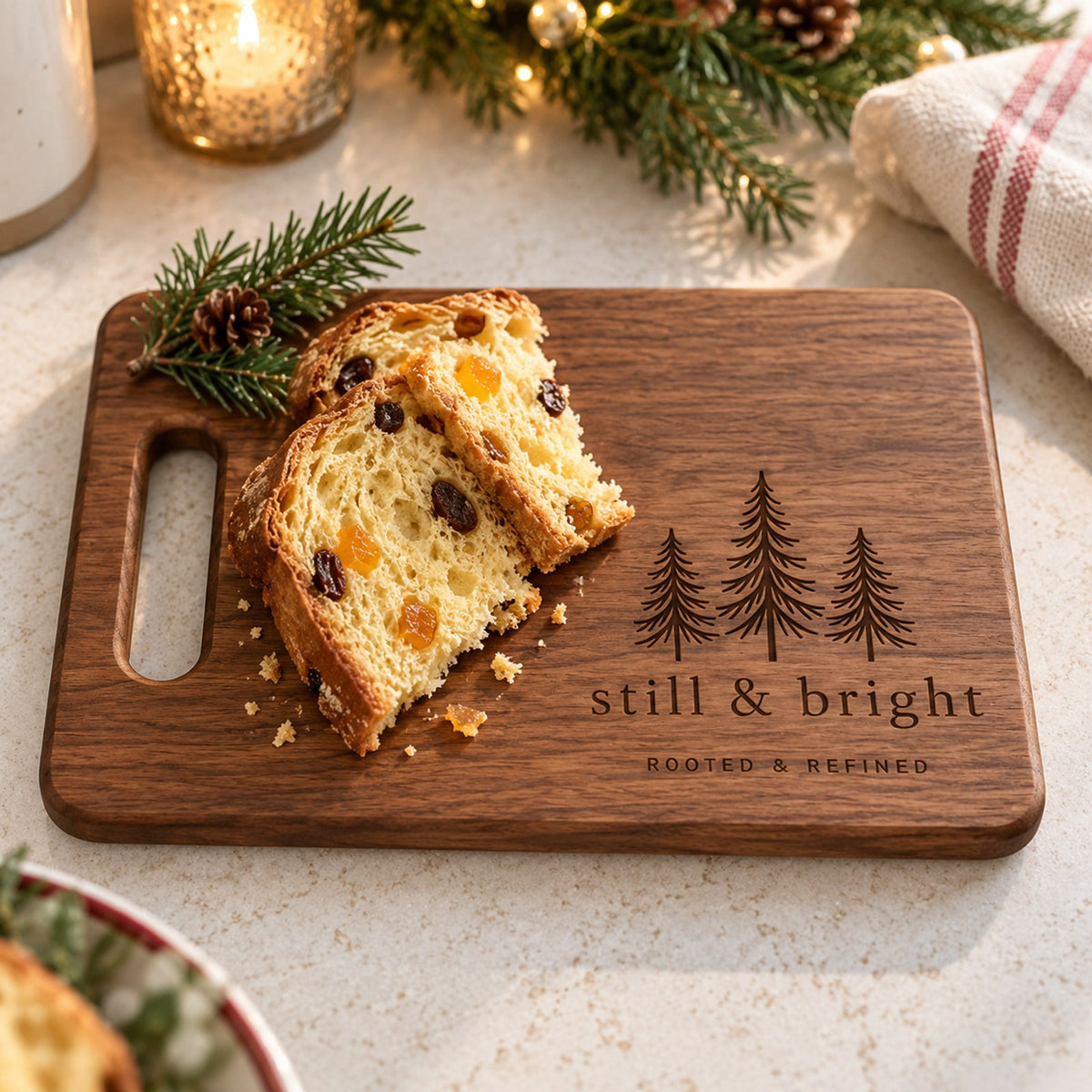 Walnut cutting board engraved with three evergreens and still & bright, with panettone and pine sprigs