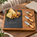 Acacia and slate charcuterie board engraved with graze., with pears, honeycomb, cheese and three cheese knives