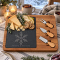 Acacia and slate charcuterie board engraved with a snowflake, with aged cheese and mulled wine by a snowy window