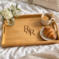 Bamboo serving tray engraved with an R&R monogram, with coffee, a croissant and flowers on a white bed