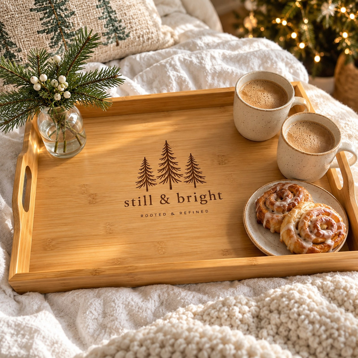 Bamboo serving tray engraved with evergreens and still & bright, with coffee and cinnamon rolls on a cozy bed