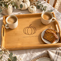 Bamboo serving tray engraved with a pumpkin, with lattes and pumpkin bread beside white pumpkins