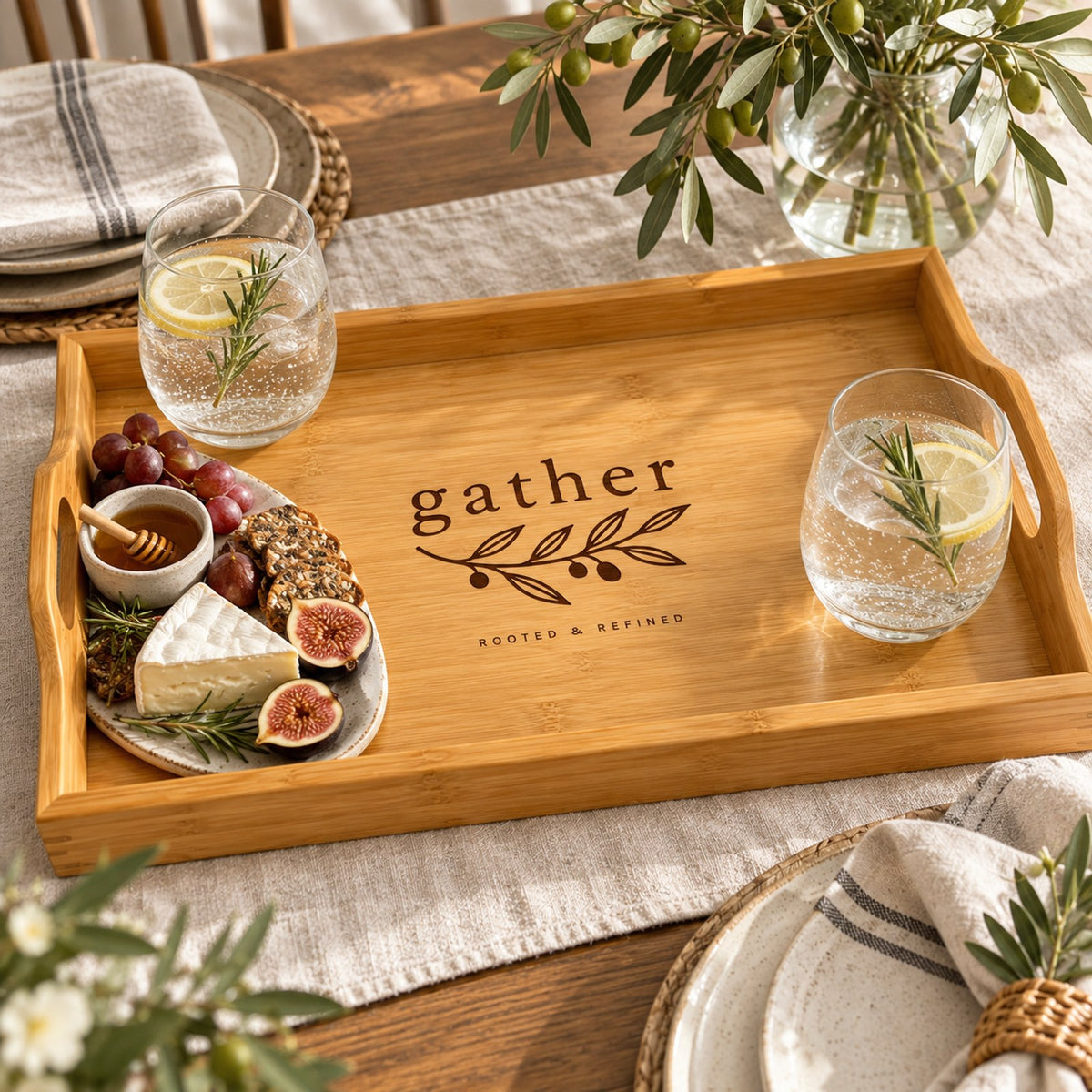 Bamboo serving tray engraved with gather and an olive branch, with figs, brie and sparkling water