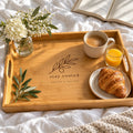 Bamboo serving tray engraved with an olive branch and stay rooted, with coffee, orange juice and a croissant