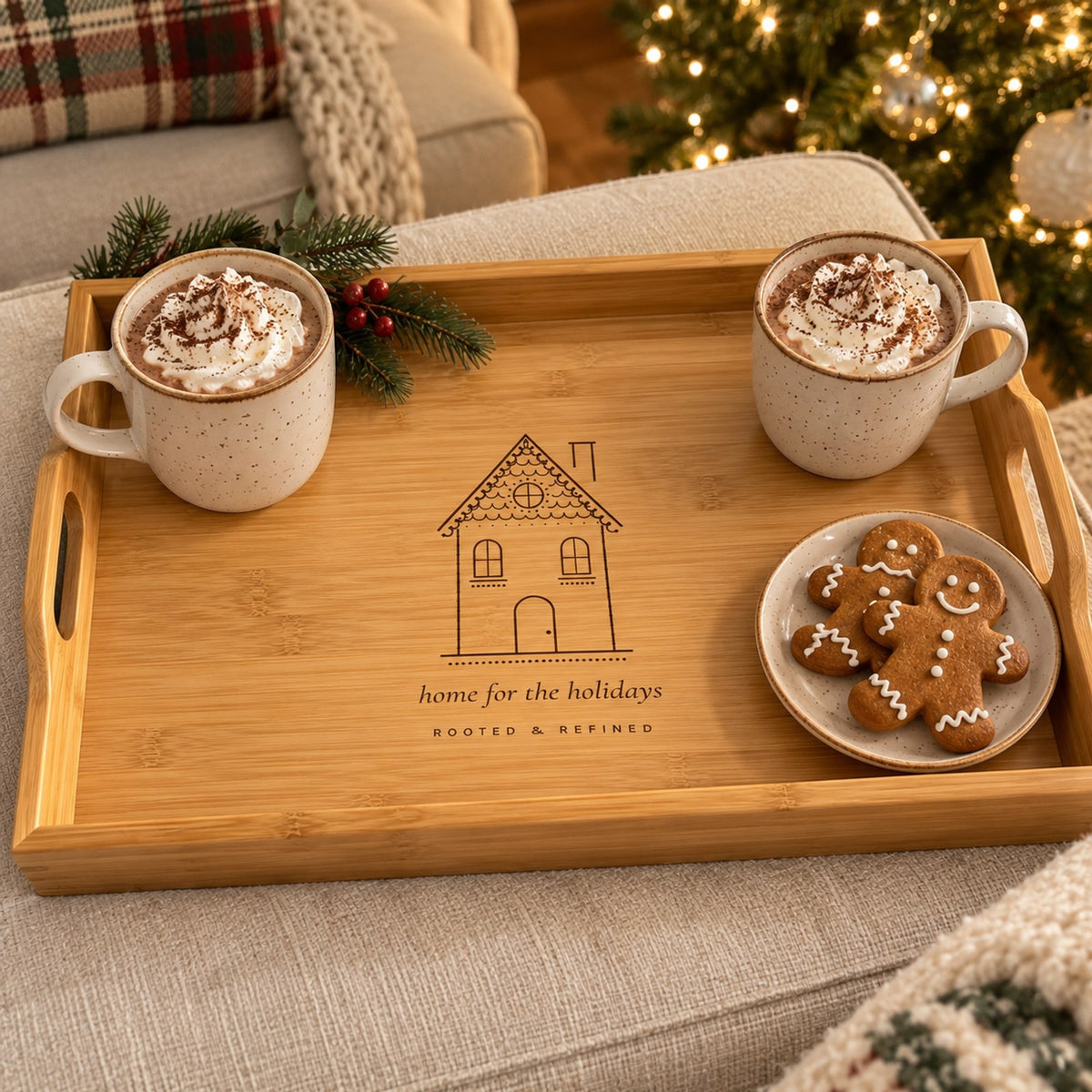 Bamboo serving tray engraved with a gingerbread house, with cocoa and gingerbread cookies by a Christmas tree