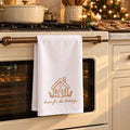 White tea towel with a gingerbread house and home for the holidays hanging on an oven in a Christmas kitchen