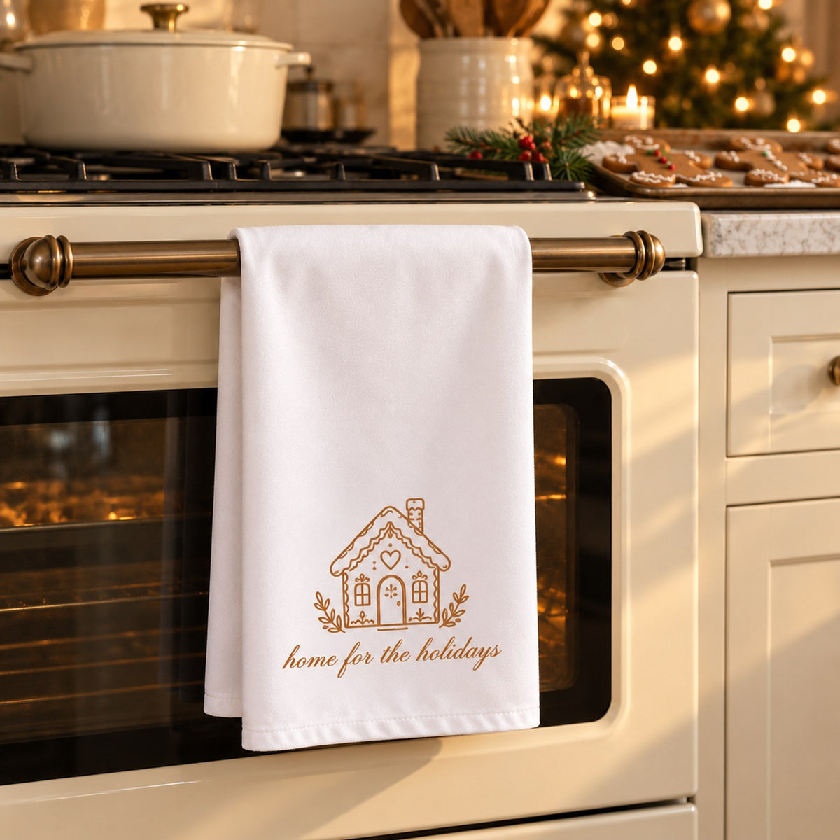White tea towel with a gingerbread house and home for the holidays hanging on an oven in a Christmas kitchen