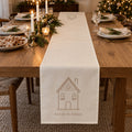 Ivory table runner with a gingerbread house and home for the holidays on a Christmas table with cookies