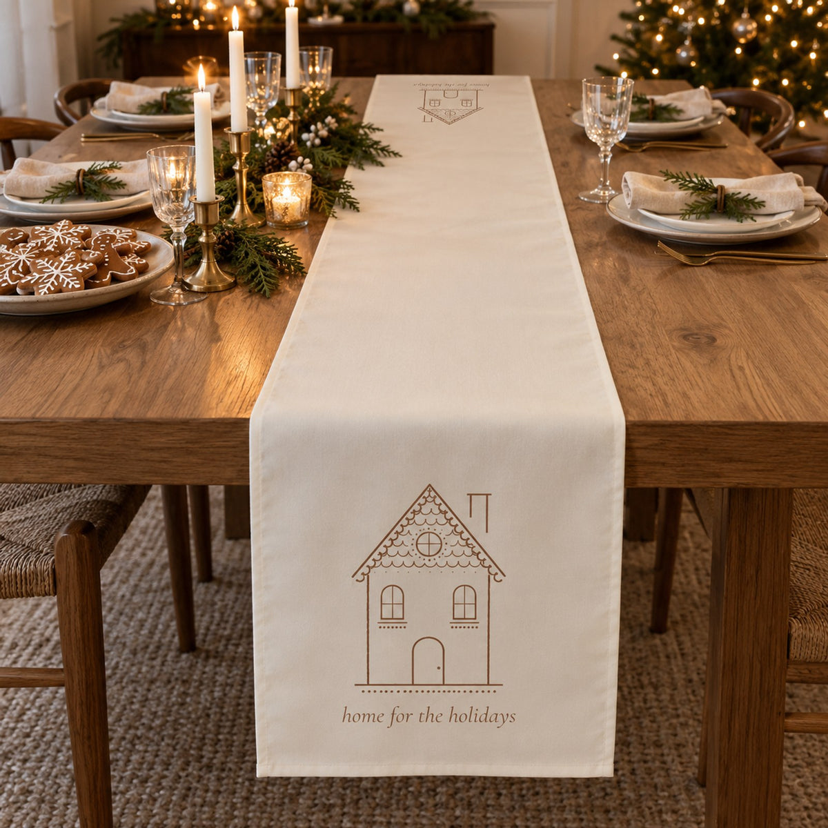 Ivory table runner with a gingerbread house and home for the holidays on a Christmas table with cookies