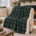 Forest green winter tartan sherpa fleece blanket draped over a cream sofa by a garland-trimmed fireplace
