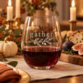 Stemless wine glass etched with gather and an olive sprig, with red wine on a candlelit fall table with figs