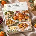 The Holiday Table: Thanksgiving to New Year's hardcover cookbook by Rachelle Merchant, two copies stacked on linen