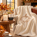 Pumpkin Cozy Night In Gift Set by Rooted & Refined: sherpa throw draped on a chair with the frosted candle and engraved mug beside it