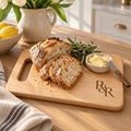 Maple cutting board engraved with the R&R monogram, with sliced sourdough, butter and rosemary on a bright kitchen counter