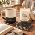 Slow Mornings coffee lover gift set: engraved speckled mug, matching coasters and a lit slow living candle beside a book