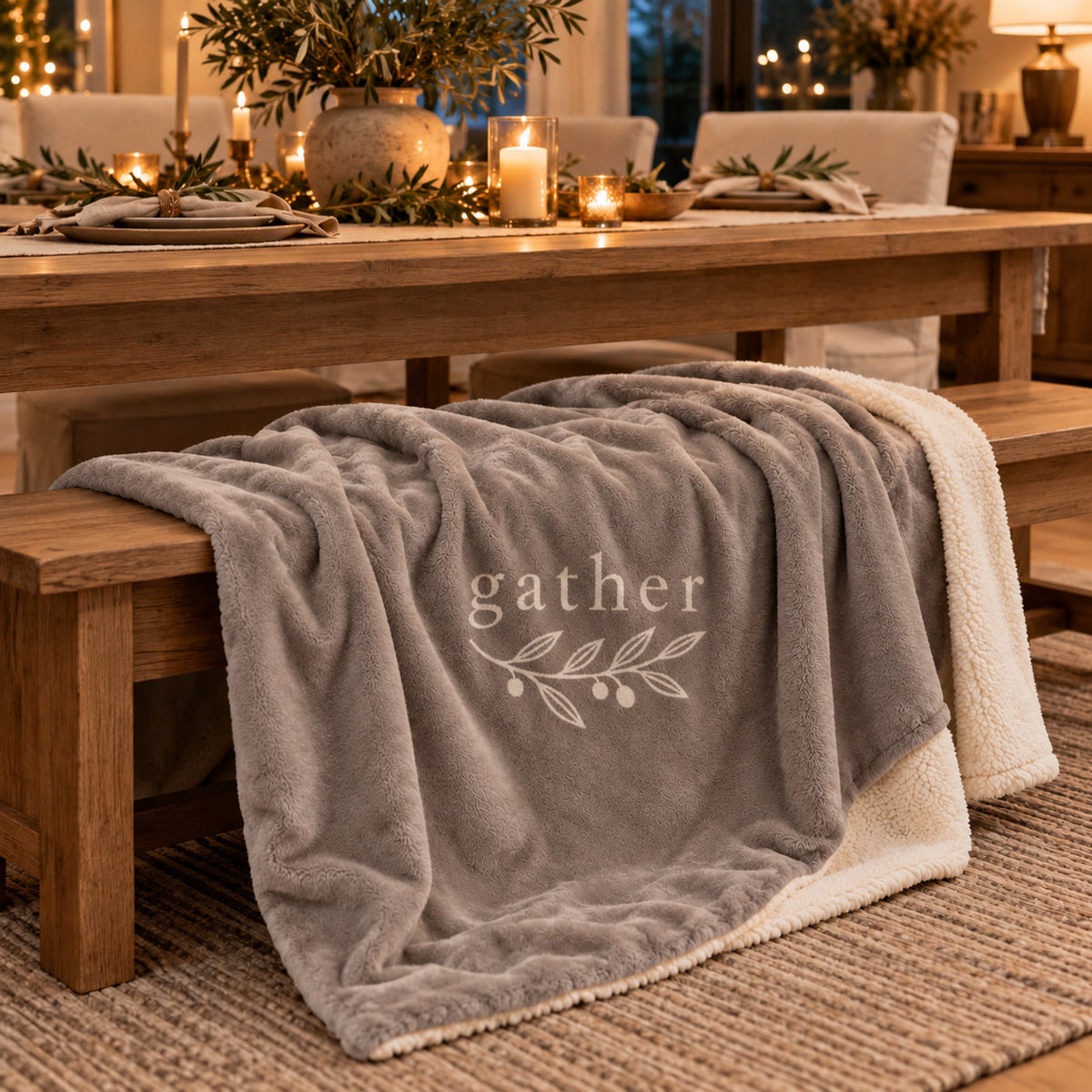 Gather Olive Branch Sherpa Fleece Blanket in Warm Grey by Rooted & Refined, draped over a dining bench