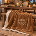 Gather Olive Branch Sherpa Fleece Blanket in Toffee by Rooted & Refined, draped over a dining bench