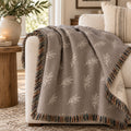 Olive Branch Woven Throw Blanket in Warm Grey, styled at home