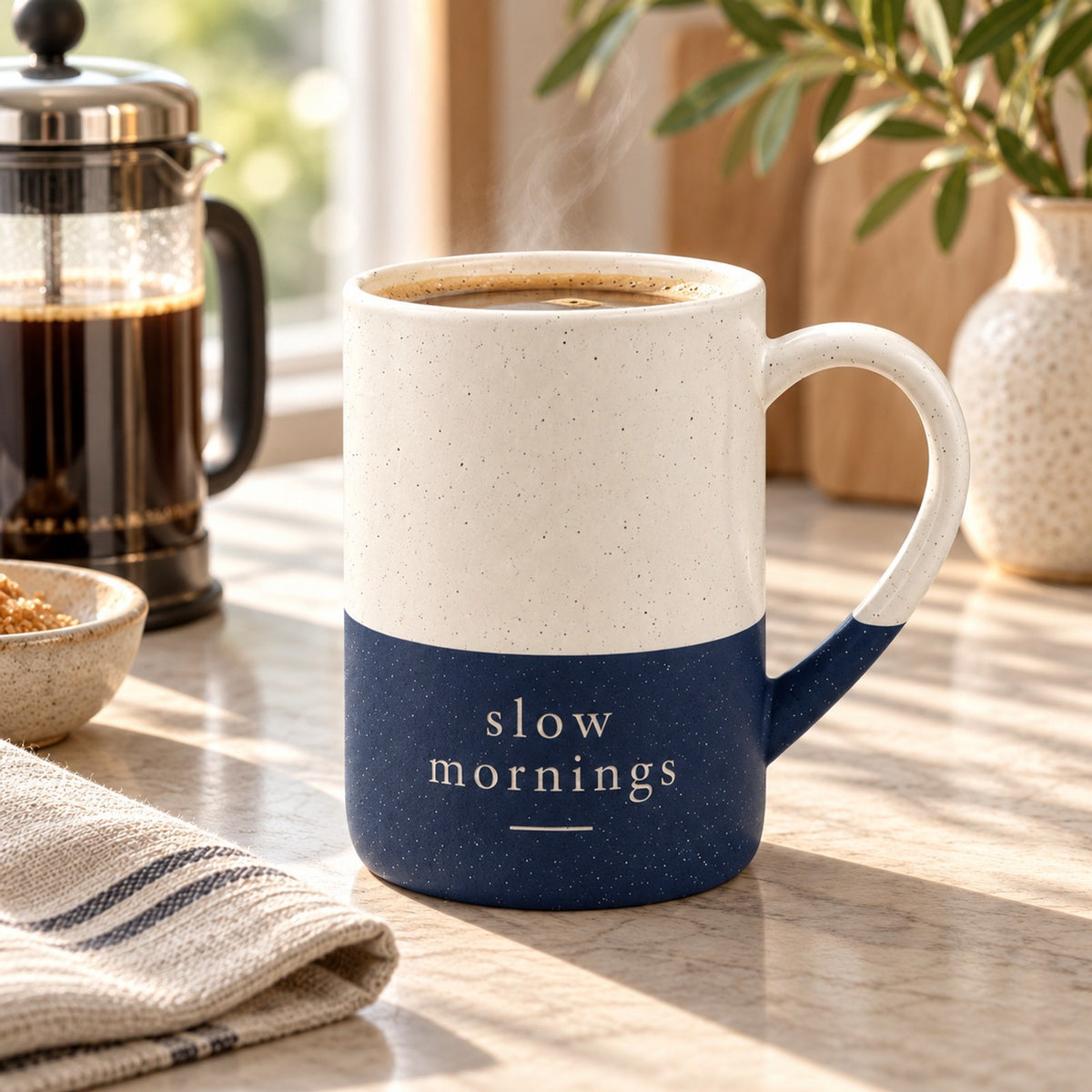 Slow Mornings engraved speckled mug in Navy Blue on a kitchen counter with a French press