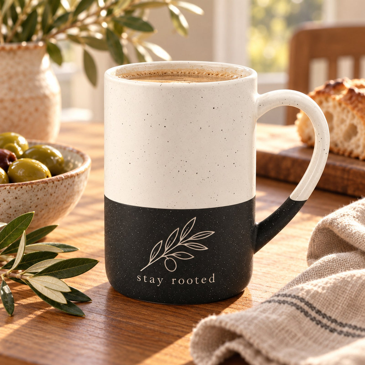 Stay Rooted olive branch engraved speckled mug in Black on a sunny breakfast table