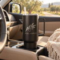 Black 40 oz tumbler with handle engraved with an olive branch, in a car cup holder